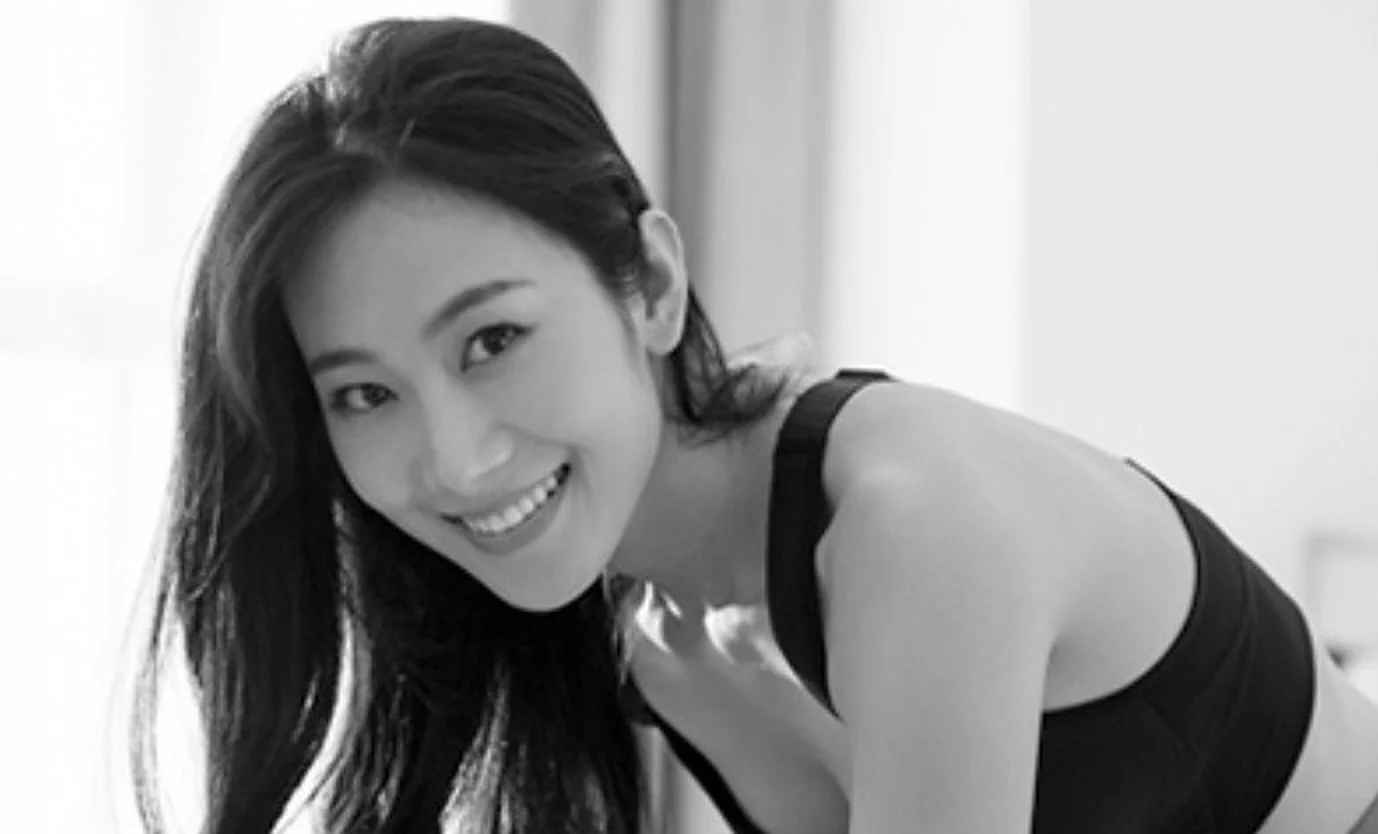 A woman smiling while lacing up her sneakers